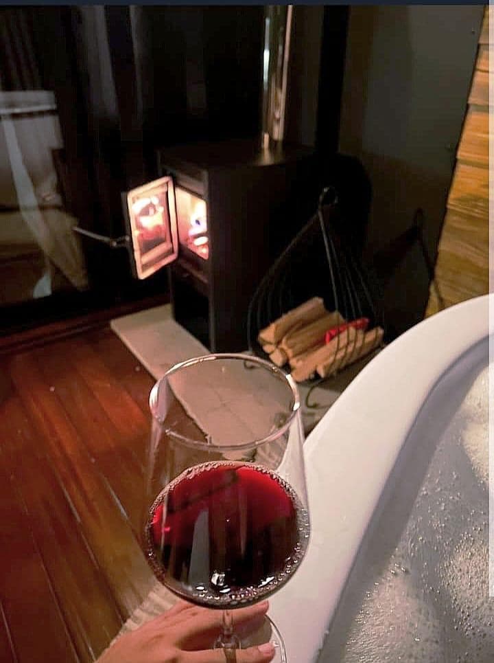 Taça de vinho tinto na banheira, com a lareira acesa ao fundo